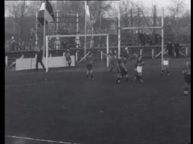Breed zwart-witfilmbeeld uit 1933 van AAC en ARVC die bij de palen rugby spelen op een Amsterdams terrein.