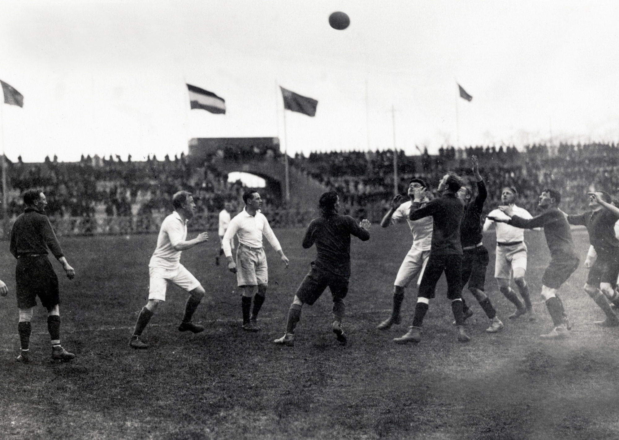 Zwart-witfoto uit 1918 van Britse geïnterneerden tijdens een rugby-line-out in Stadion Amsterdam, met de bal hoog boven de spelers en volle tribunes op de achtergrond.