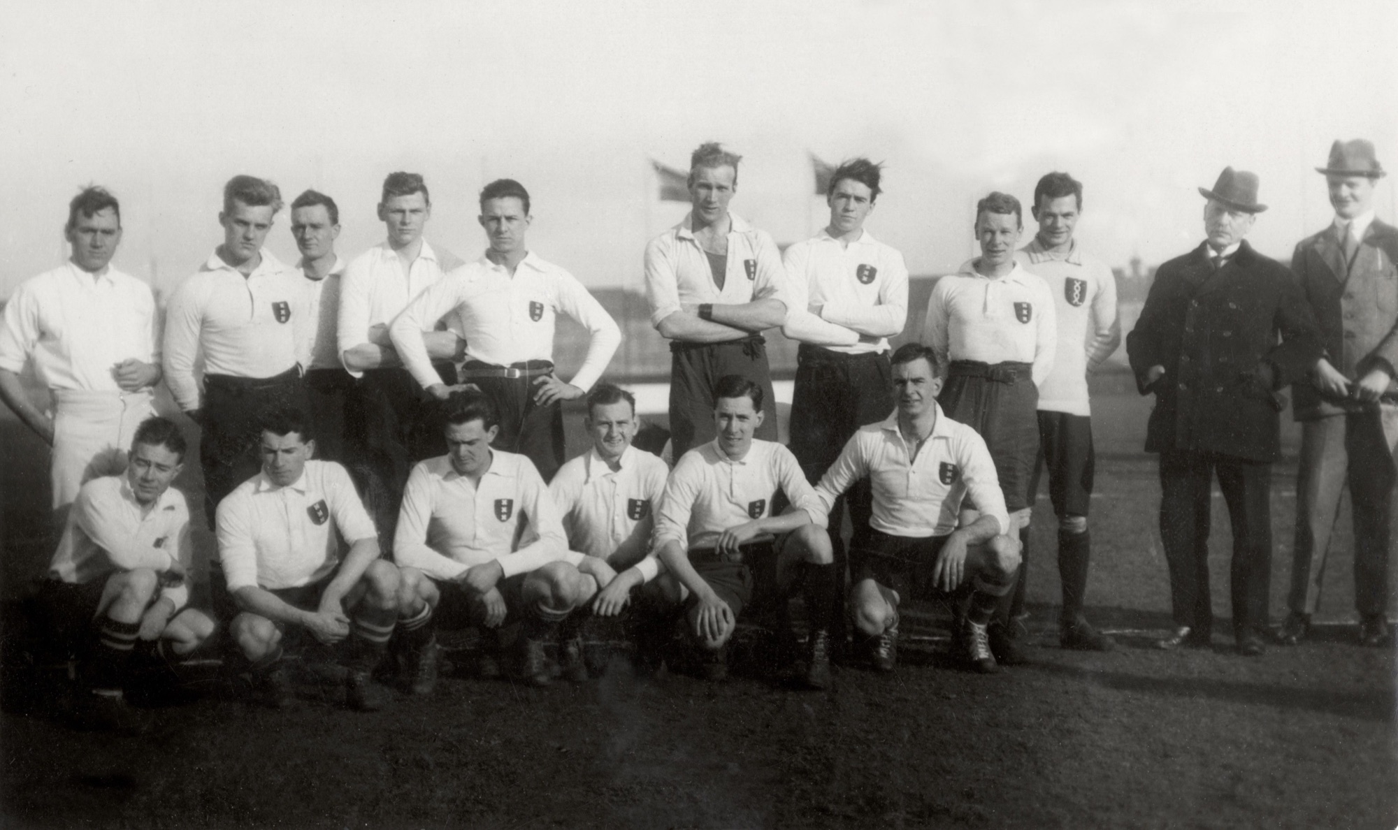 Zwart-wit teamportret uit 1921 van het Amsterdamse rugby-XV, met spelers in lichte shirts in twee rijen in Stadion Amsterdam.