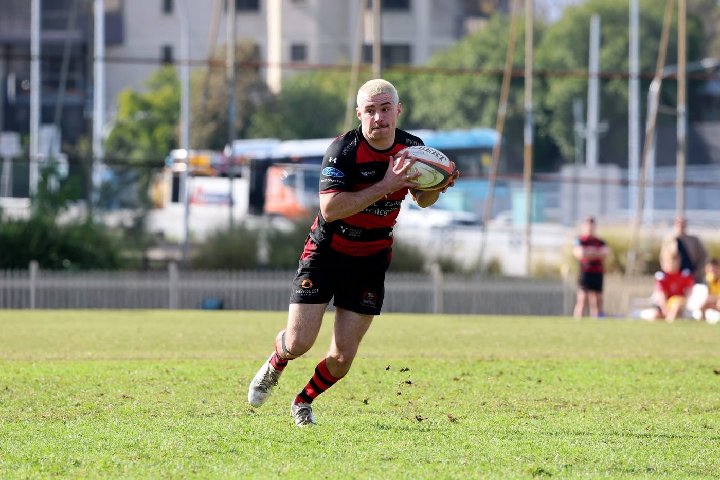 Harry White loopt in open spel op de bal in, in rood-zwart gehoepeld clubtenue