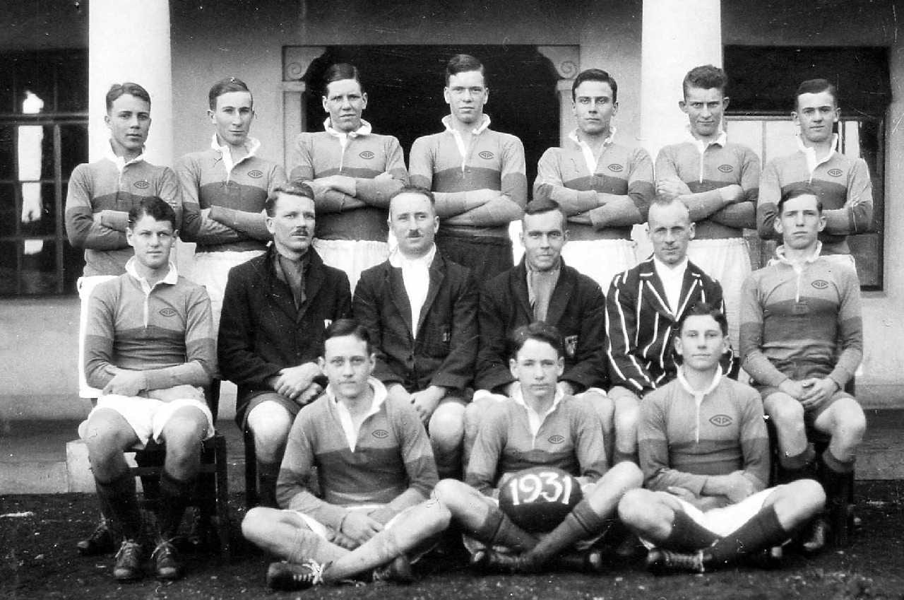 Teamfoto van AAC Rugby uit 1931: spelers in hoepelshirts met clubbestuurders en een wedstrijdbal met het jaartal 1931.