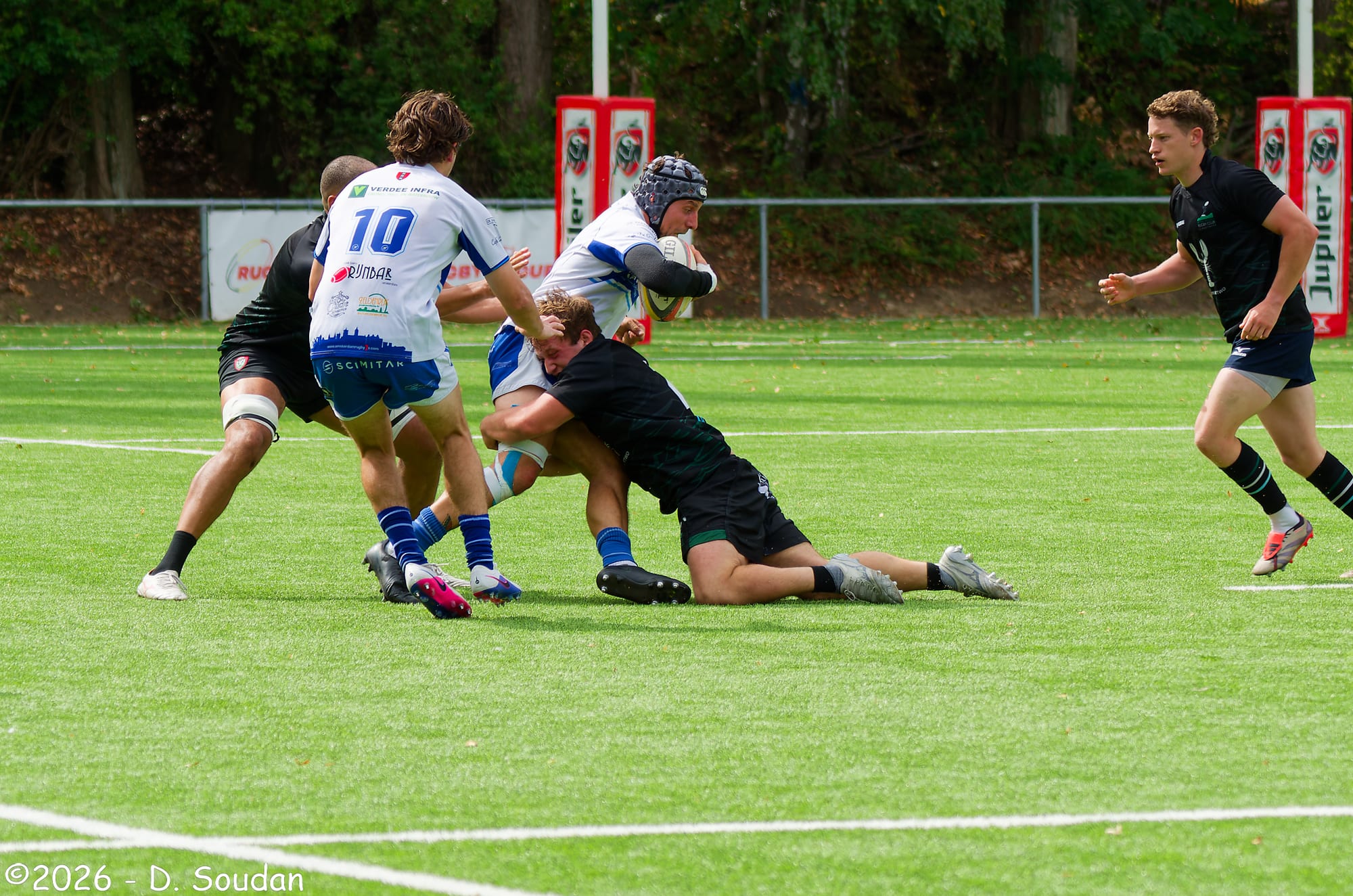AAC-spelers in wit-blauw wedstrijdtenue rond de bal tegen Royal Kituro