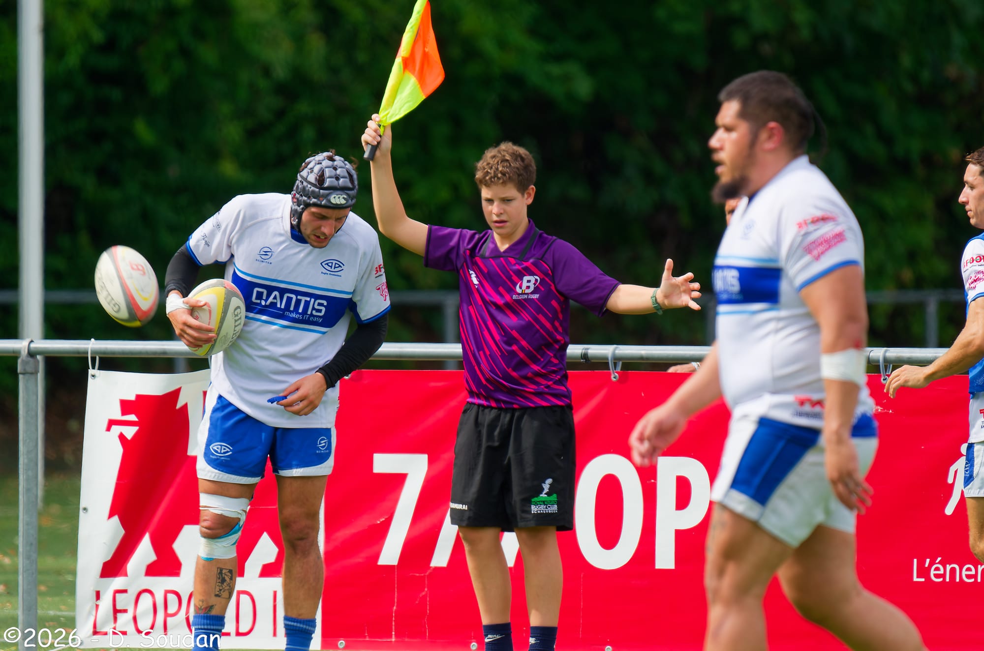 Een AAC-speler in wit-blauw wedstrijdtenue en een blauwe scrumcap tijdens de oefenwedstrijd tegen Royal Kituro