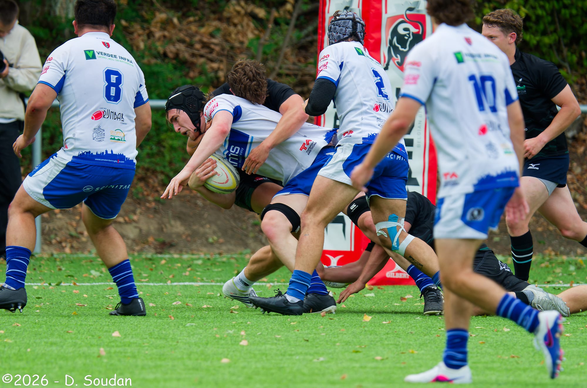 Een AAC-speler in wit-blauw wedstrijdtenue in contact met de bal tegen Royal Kituro
