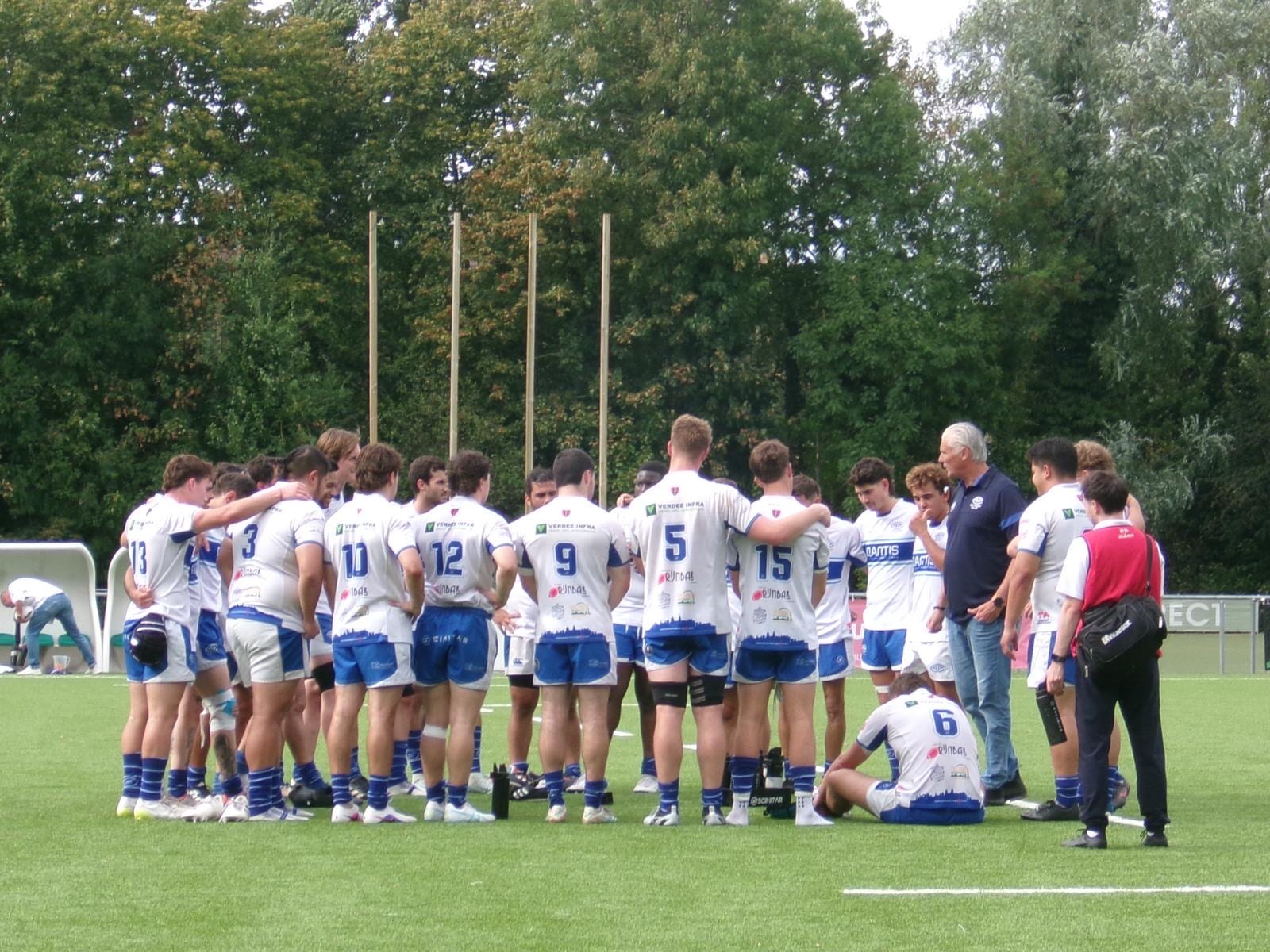 AAC-spelers in een huddle op het veld tijdens de oefenwedstrijd tegen Royal Kituro