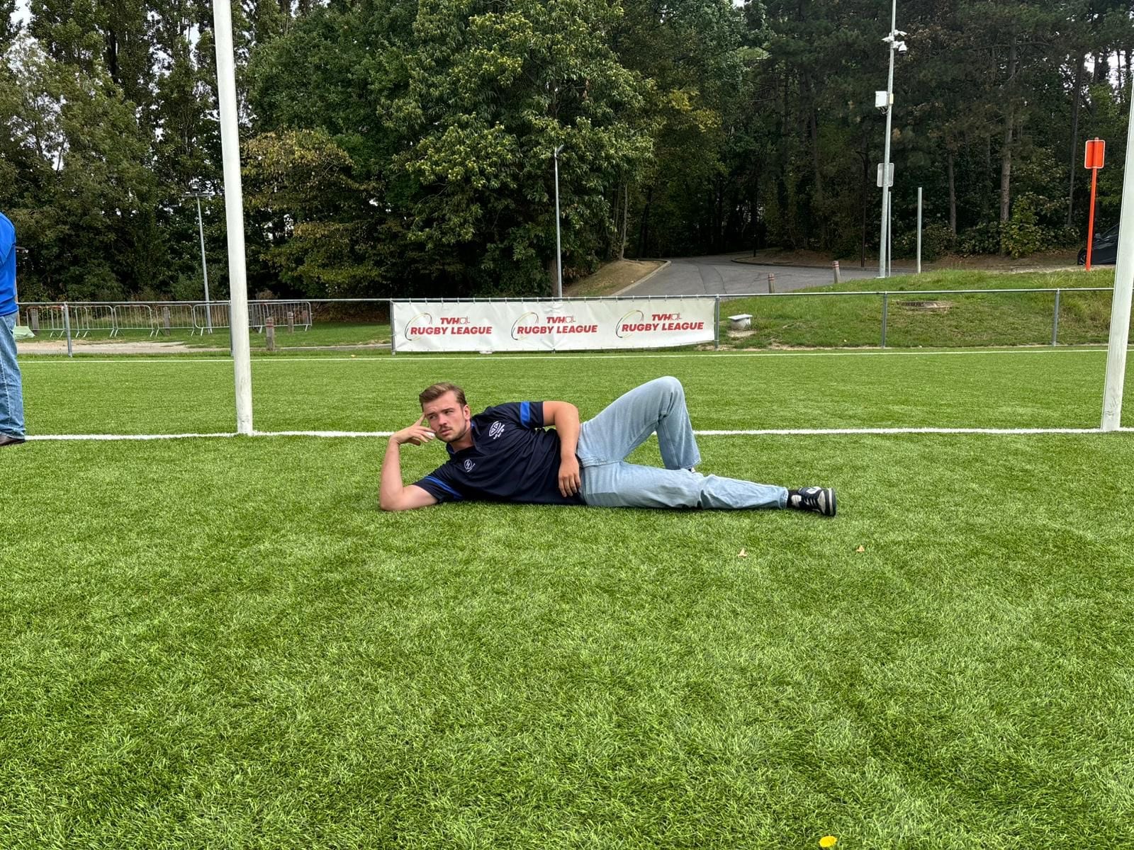 Een AAC-speler in clubkleding liggend op het veld na de oefenwedstrijd tegen Royal Kituro