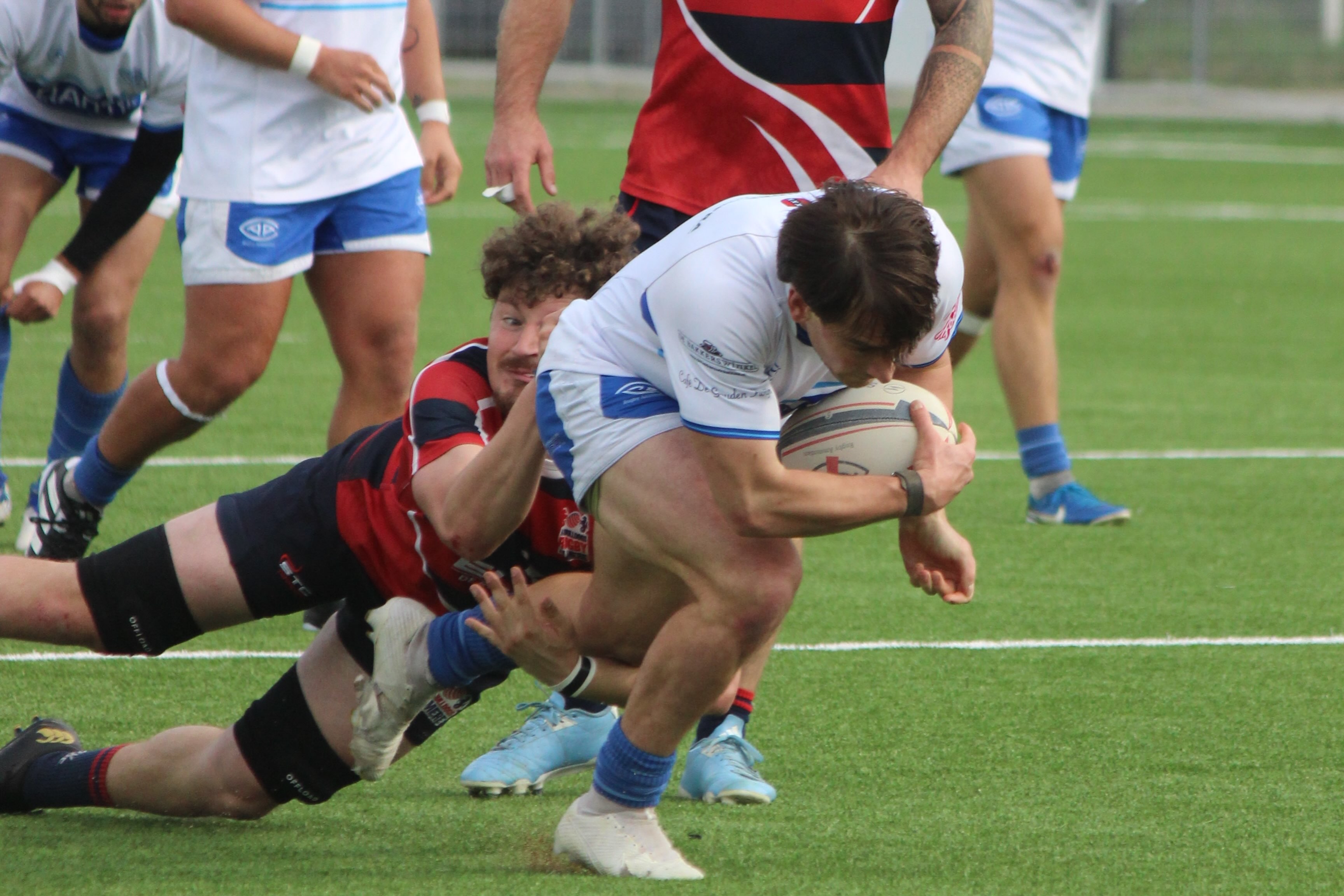 Een AAC-speler in donkerblauw tenue loopt met de bal tegen RC Bulldogs